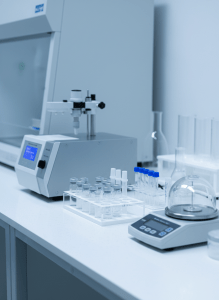 A close-up of a bright, clean scientific laboratory showing precision lab equipment, glass vials, and peptide research tools on a white surface. Crisp, clear lighting, minimal white and light grey tones, scientific and premium aesthetic. Depth of field blur in background.
